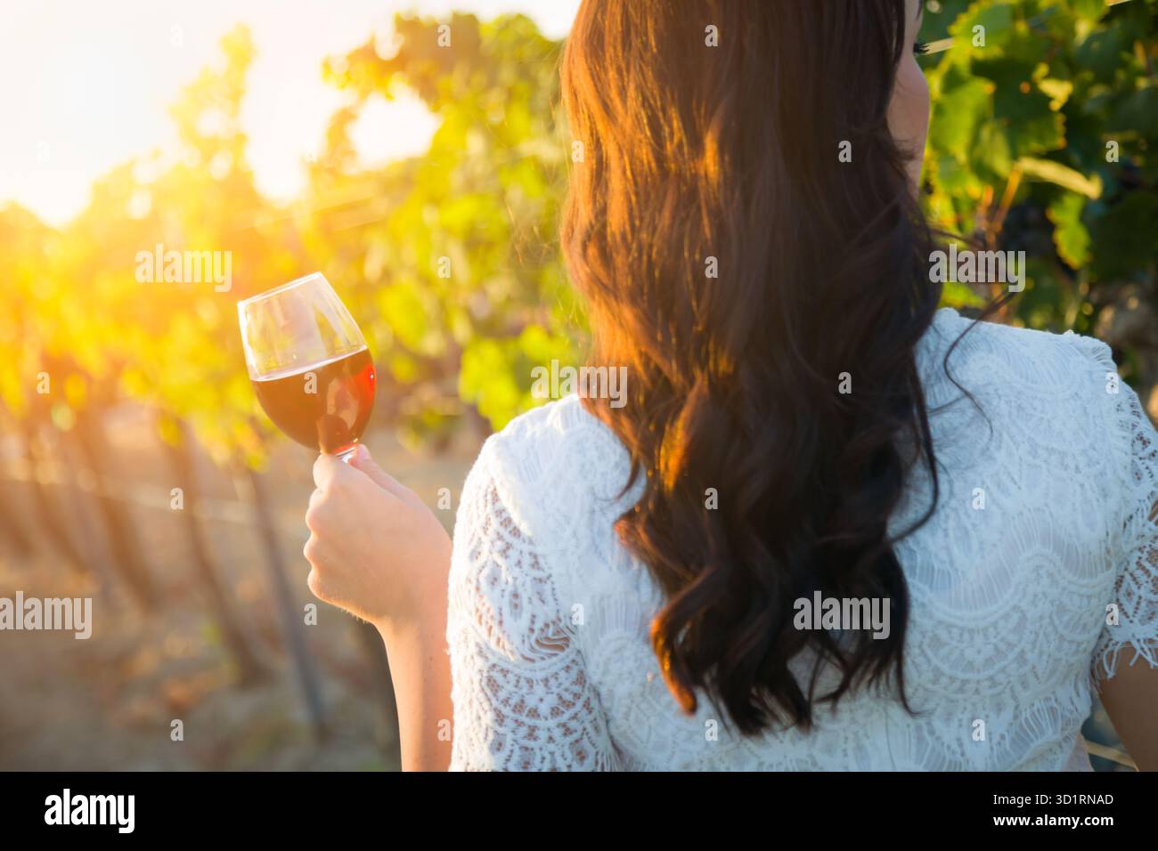 Junge Erwachsene Frau genießt eine Weinverkostung bei einem Spaziergang im Weinberg Stockfoto