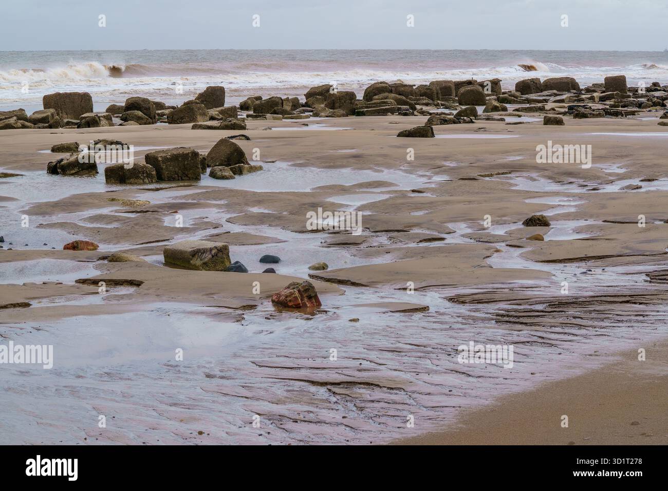 Gezeitenbecken bilden sich zwischen verwitterten Felsen an der einsamen britischen Küste bei Spurn Head, Yorkshire, Großbritannien. Stockfoto