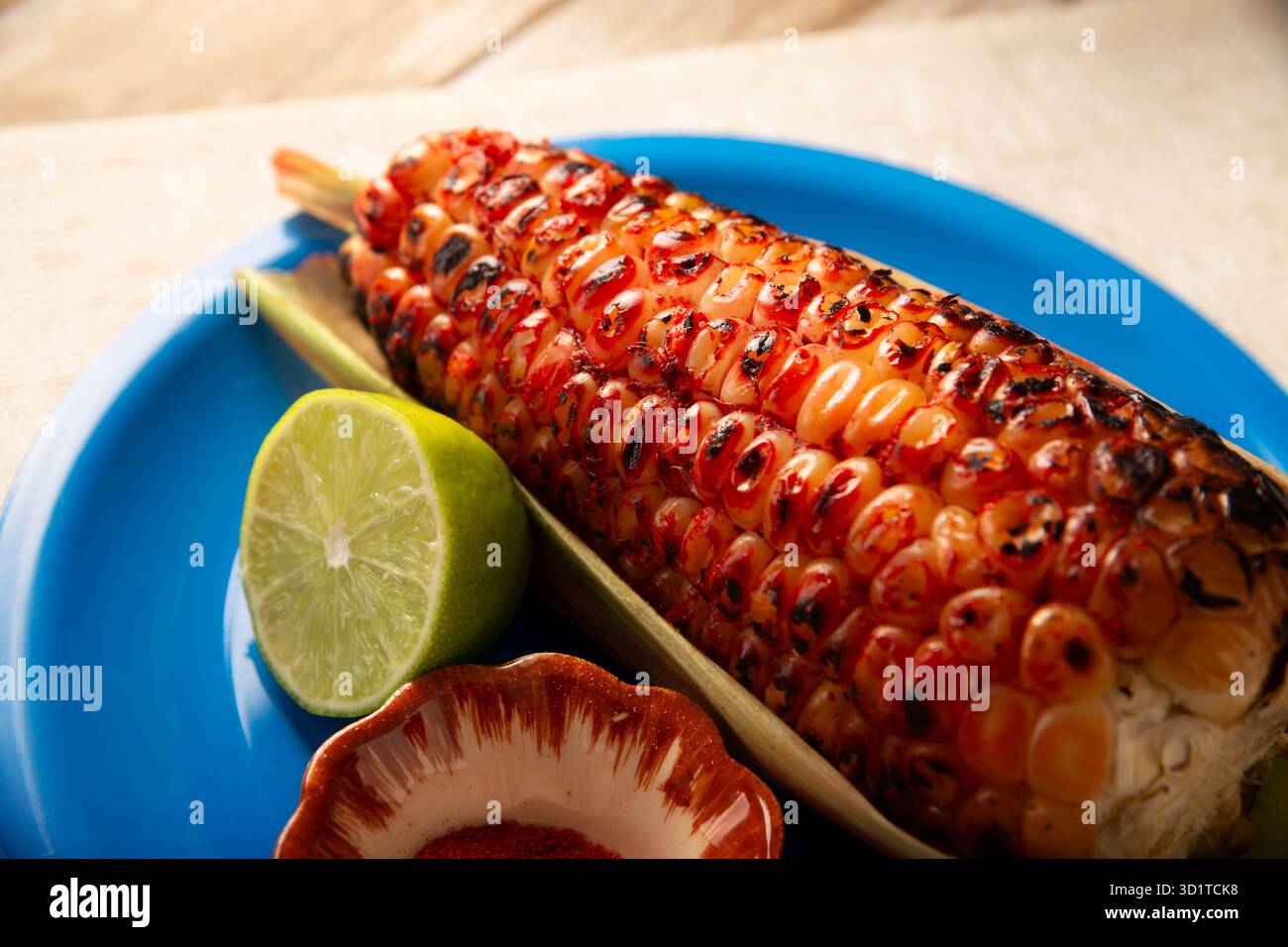 Mexikanischer gegrillter Maiskolben. Ein typisches mexikanisches Street Food, wo es als Elote Asado bekannt ist. Es ist ein auf Holzkohle gegrillter Maiskolben, der mit Limette und piquín gegessen wird Stockfoto