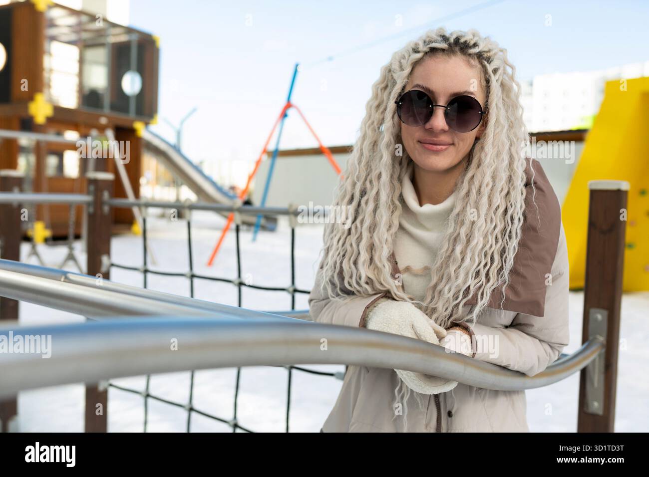 Frau mit weißem Haar und Sonnenbrille auf dem Spielplatz Stockfoto