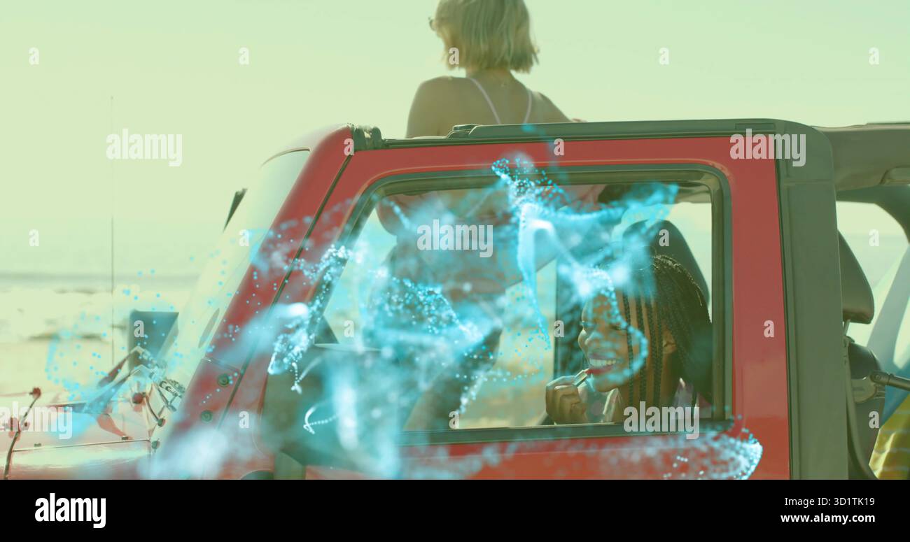 Zwei Freunde tragen Lippenstift auf und blicken auf das Meer in rotem Cabrio am Strand, unter blauem Überzug Stockfoto