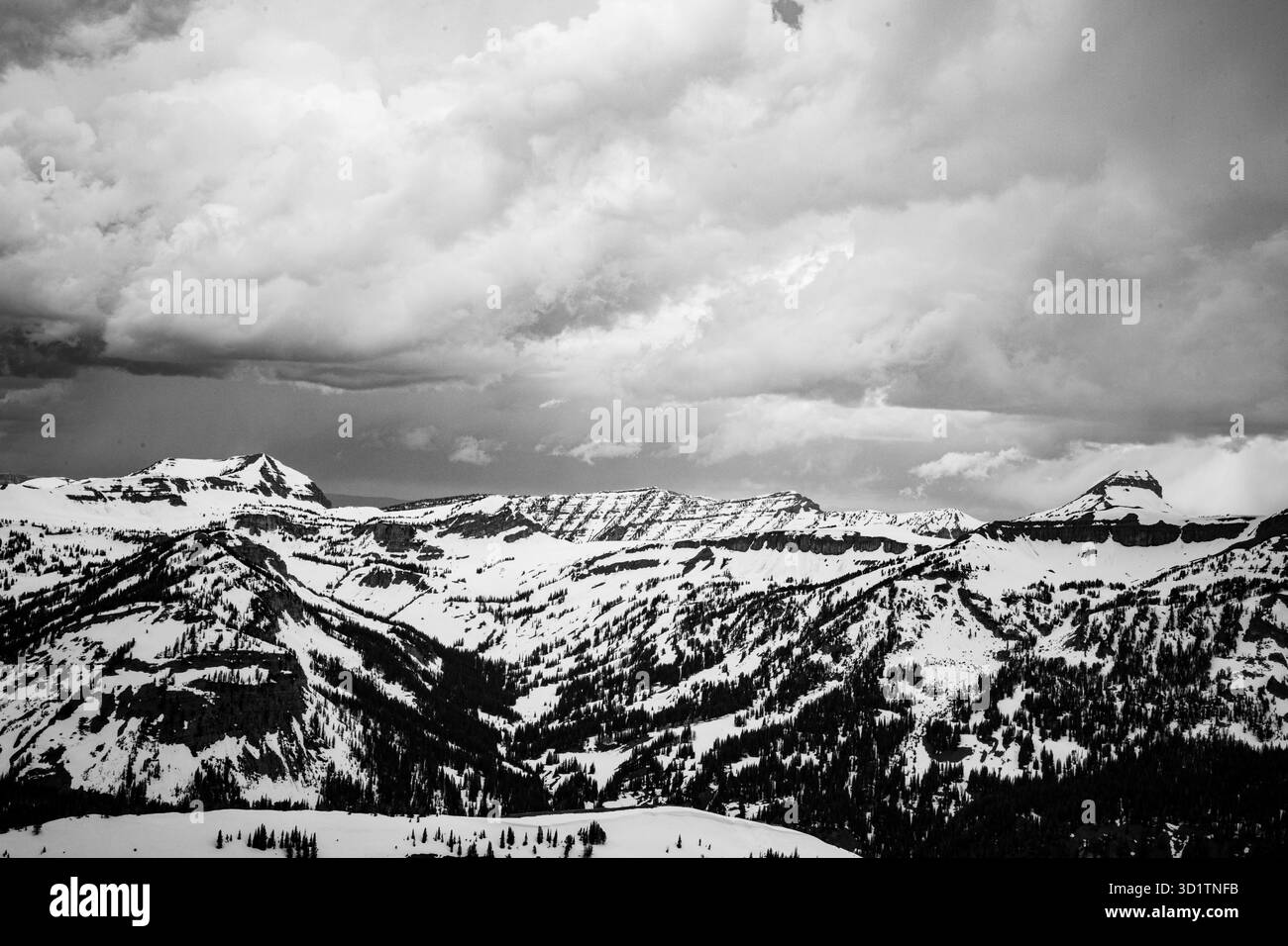 Schwarzweiß-Foto von schneebedeckten Gipfeln in der Grand Teton Mountain Range in Wyoming, USA, mit dramatischen Sturmwolken. Stockfoto