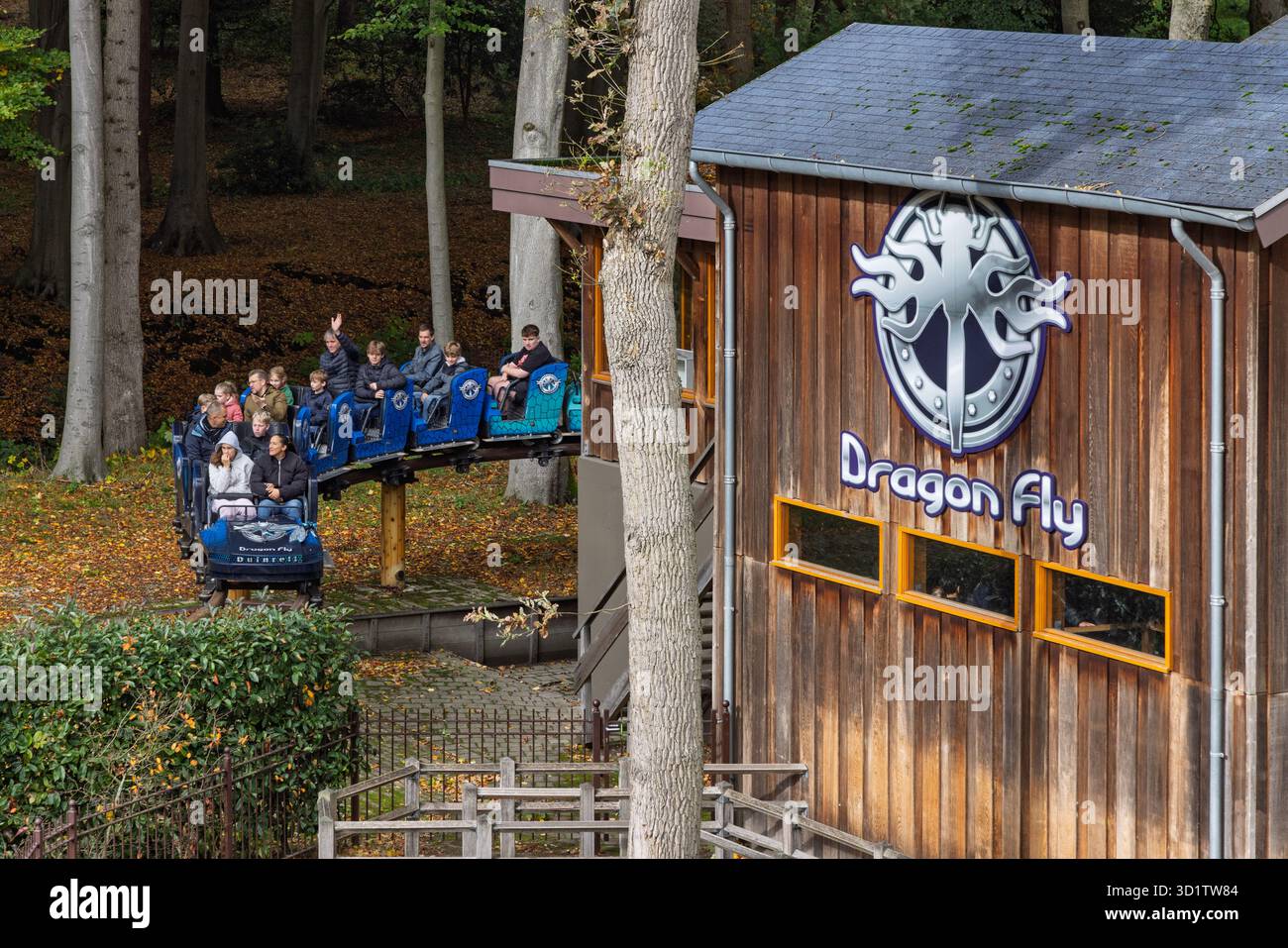 Die Achterbahn Dragon Fly gleitet durch einen dichten Wald, vorbei an der hölzernen Fahrstation, wobei die Passagiere die Streckenführung am DUI genießen Stockfoto