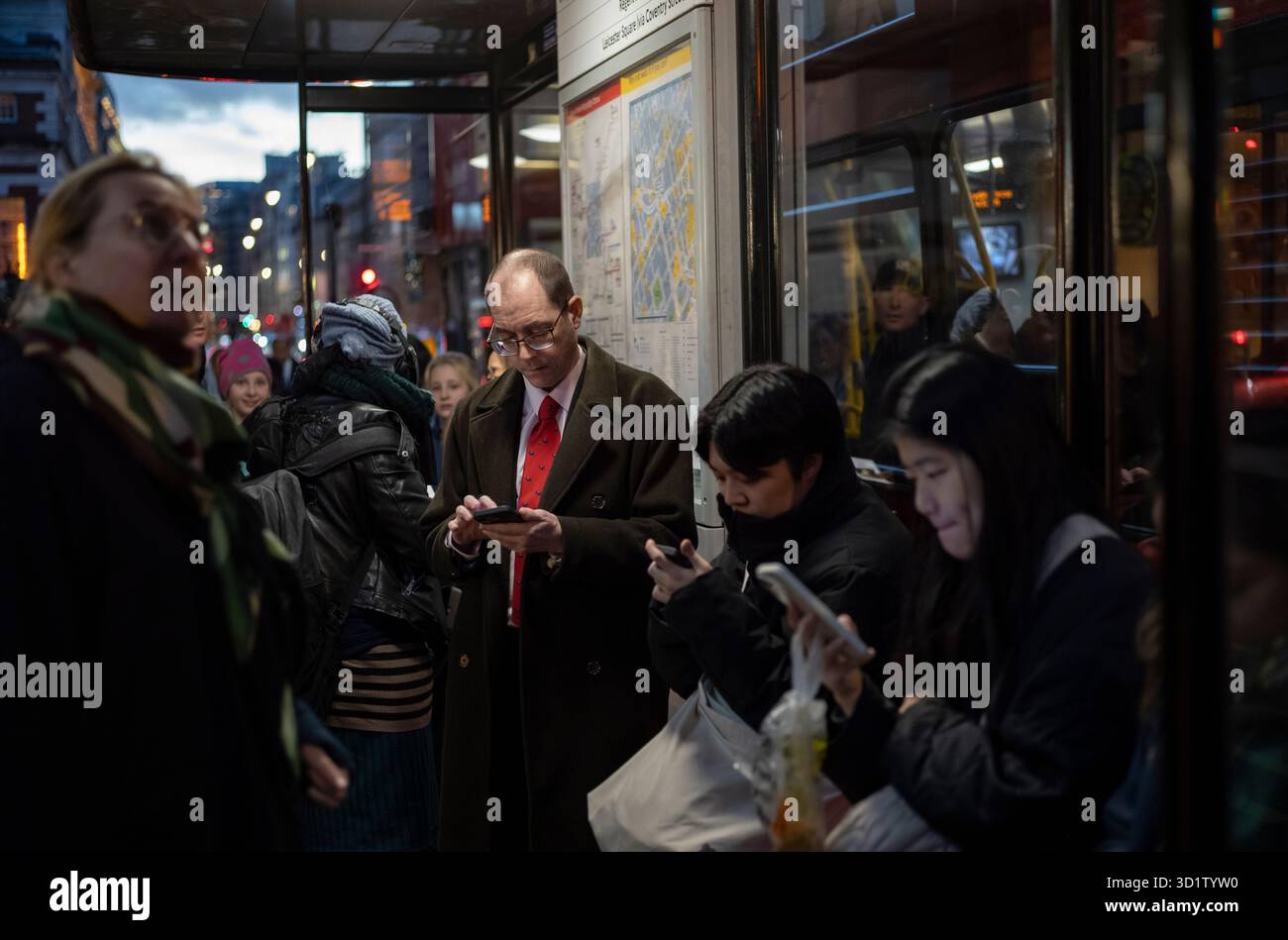 Londoner Pendler stehen in einer Bushaltestelle, die während der Hauptverkehrszeit in einem Londoner Bus im Herzen von Mayfair, ventral London, England, Großbritannien, nach Hause fahren Stockfoto