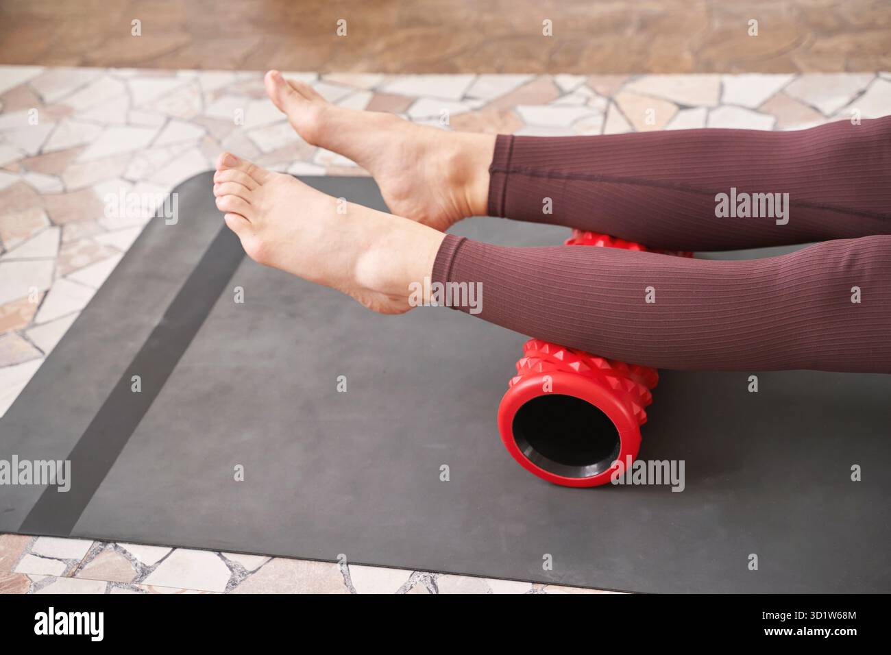 Junge Frau dehnt den Körper auf einer Fitnessmatte. Myofasziale Freisetzungsmassage Stockfoto