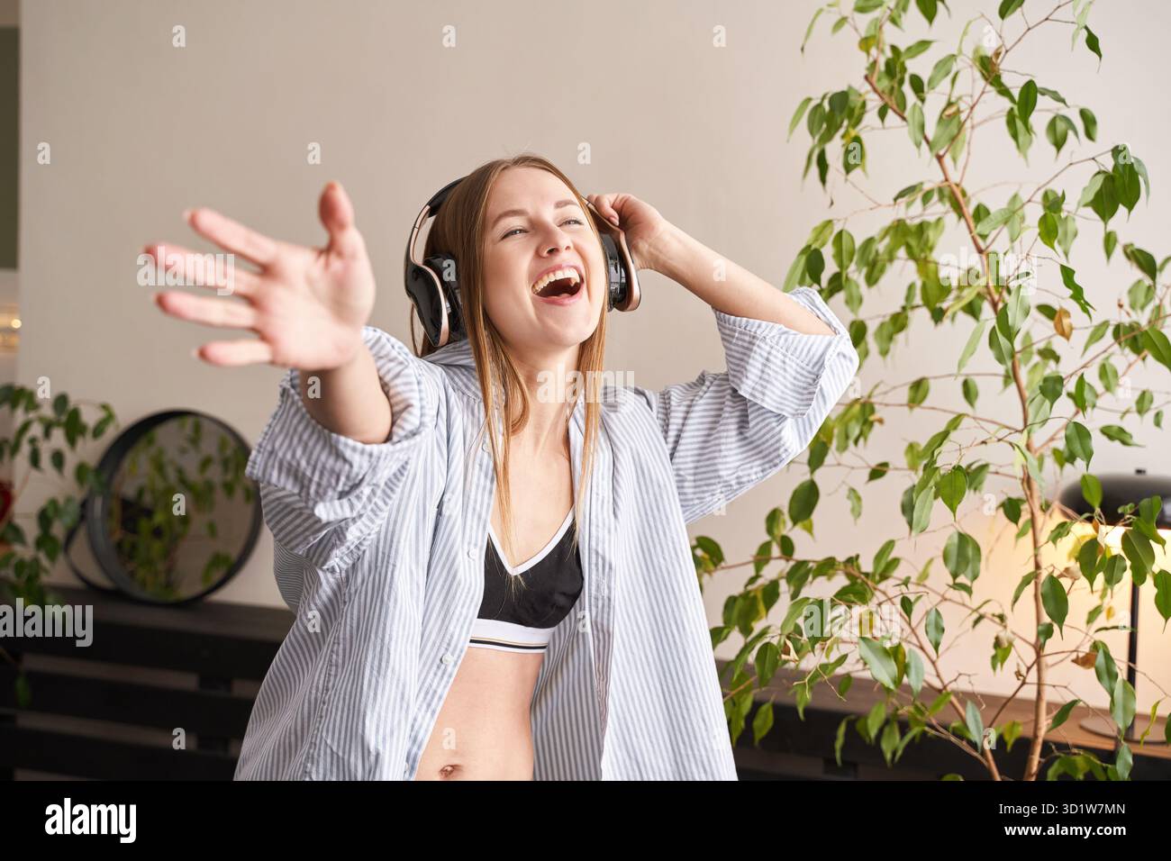 Junge Frau singt zu Hause. House Lyrics tanzen. Lustiges Lied. Unabhängiges Hochformat Stockfoto