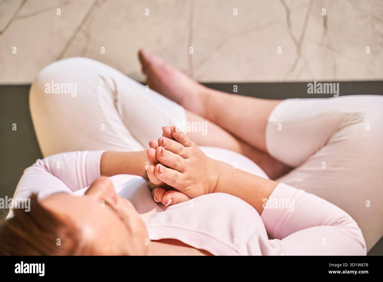 Junge Schwangerin geht Yoga-Übung in der Küche. Gesundheitswesen Online-Unterricht Stockfoto