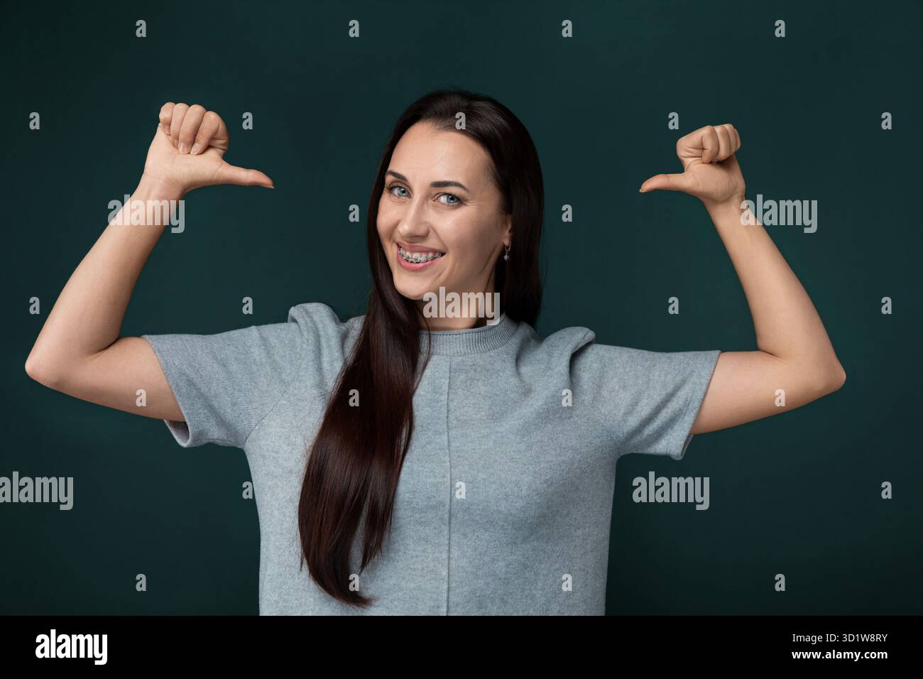Frau mit langen braunen Haaren, die Arme in der Luft hält Stockfoto