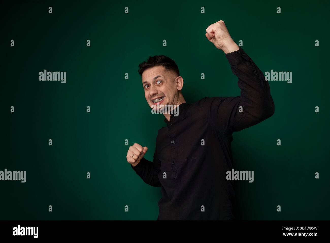 Mann in schwarzem Hemd hebt die Faust Stockfoto