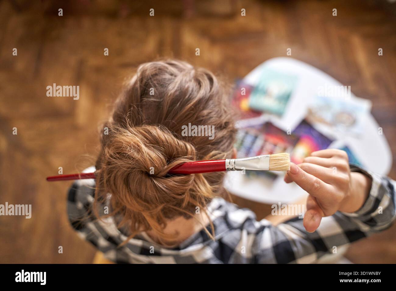 Frau, die Pinsel am Kopfhaar hält. Aquarell. Zeichenprozess Stockfoto