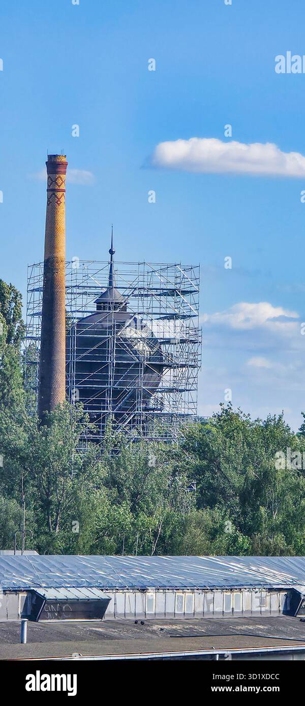 Berlin, Deutschland - 04. Juli 2025: Historisches Gebäude wird restauriert, mit Gerüsten umgeben von üppig grünen Bäumen und blauem Himmel. - Smartphone-aufgenommenes Stockfoto