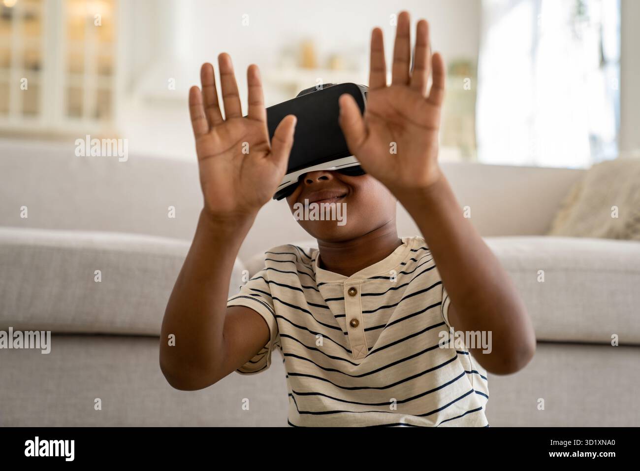 Ein kleiner, neugieriger afroamerikanischer Junge mit VR-Brille, der Zeit in der virtuellen Welt verbringt Stockfoto