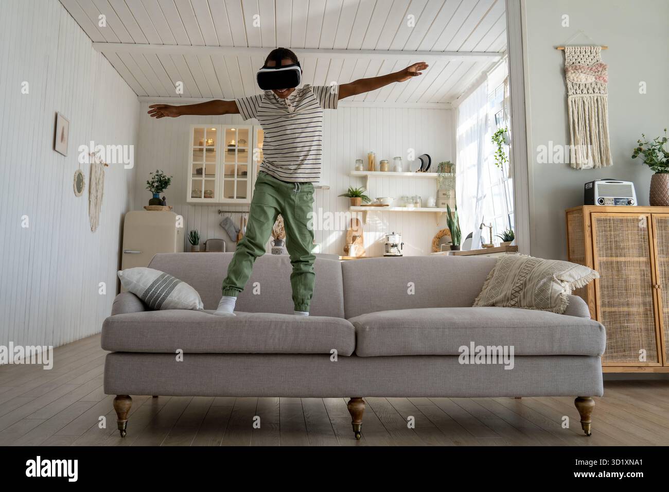 Ein sorgenfreies afrikanisches Kind, das VR-Helm für Spaß und Unterhaltung benutzt und im Metaversum fliegt Stockfoto