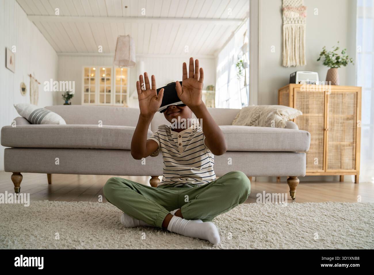 Ein kleiner, neugieriger afroamerikanischer Junge mit VR-Brille, der Zeit in der virtuellen Welt verbringt Stockfoto