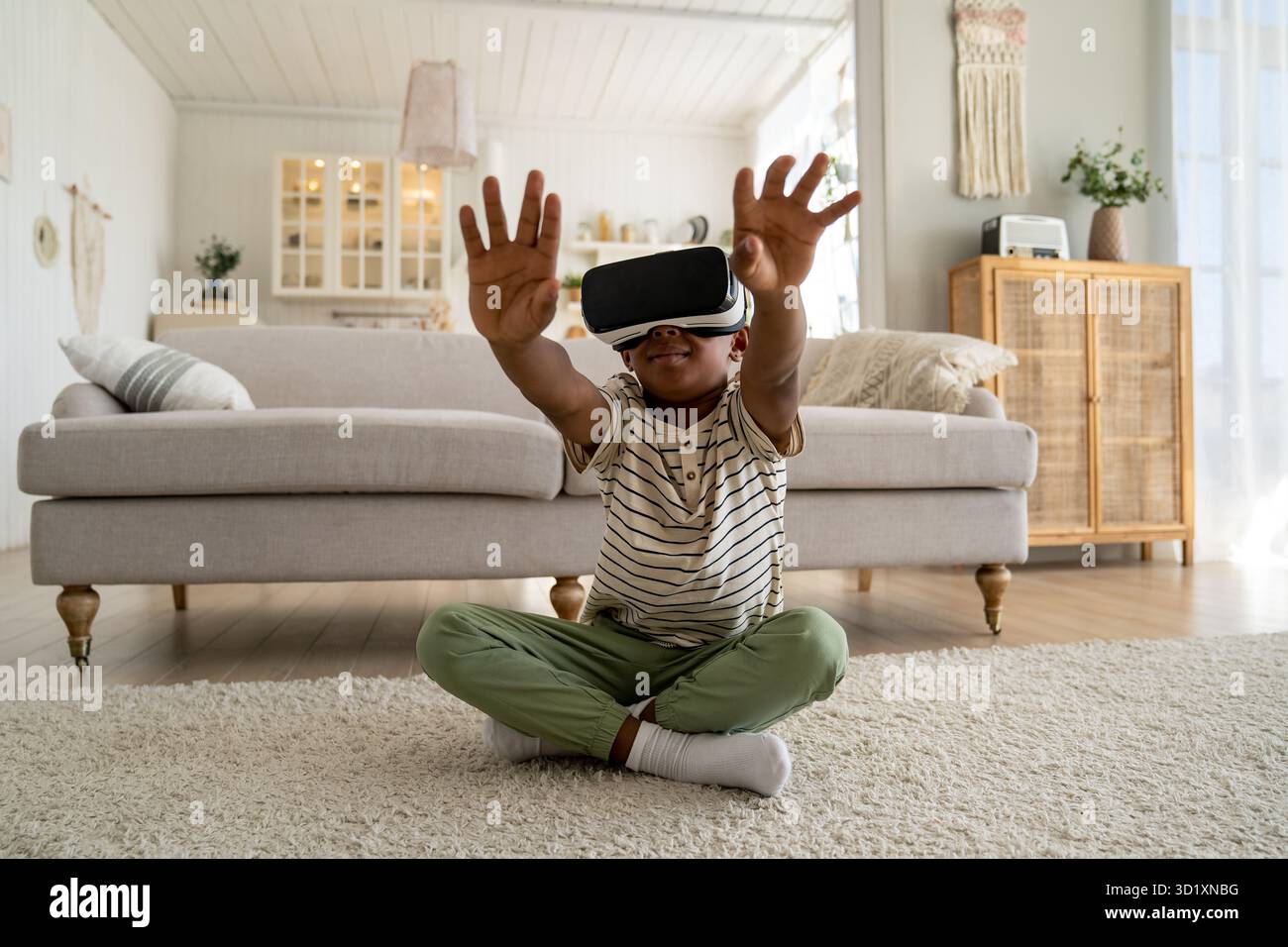 Ein glücklicher afroamerikanischer Junge in einer Virtual-Reality-Brille, der zu Hause den Metaverse erforscht Stockfoto