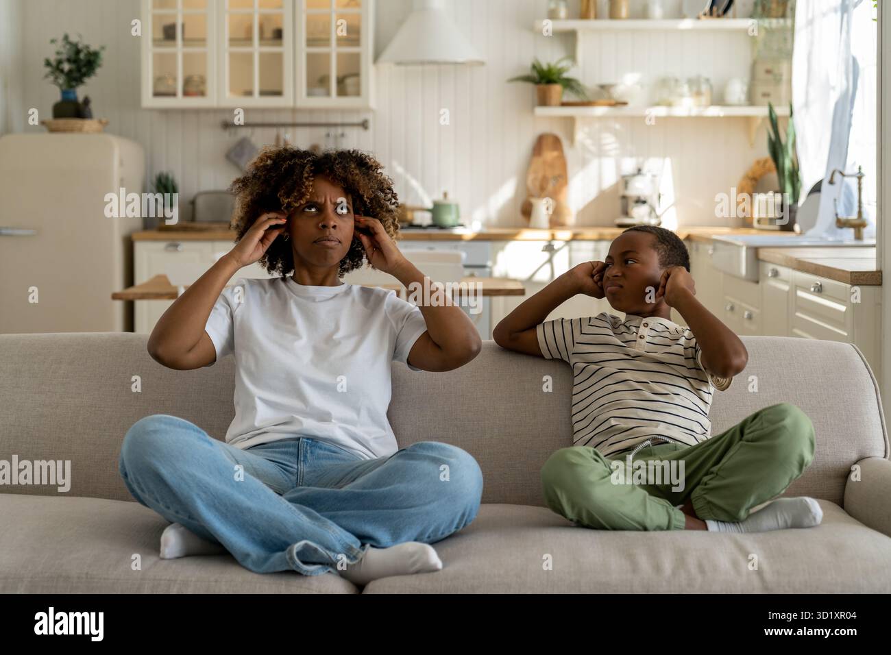 Unglückliche afroamerikanische Familie Mutter und Sohn sitzen auf dem Sofa und bedecken die Ohren, die von lauten Nachbarn verärgert wurden Stockfoto