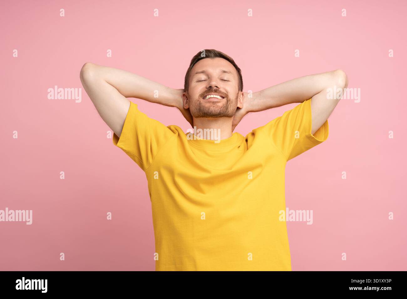 Glücklicher lächelnder Kerl auf rosafarbenem Hintergrund. Zufriedenheit, Glück, Zufriedenheit, Euphorie, Ekstase. Stockfoto