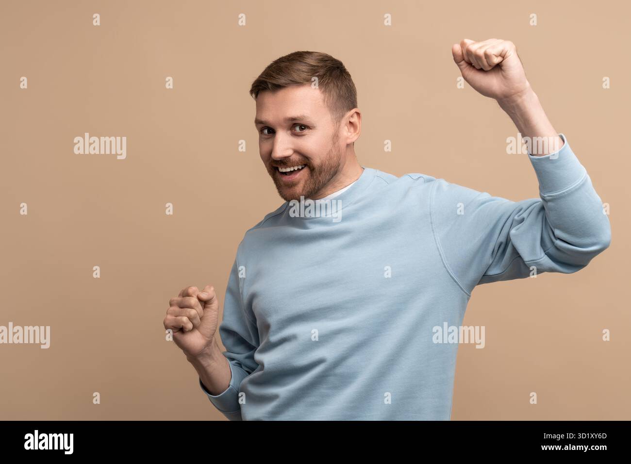 Überglückter glücklicher Mann, der Siegesgeste auf beigefarbenem Hintergrund zeigt und in die Kamera schaut. Stockfoto