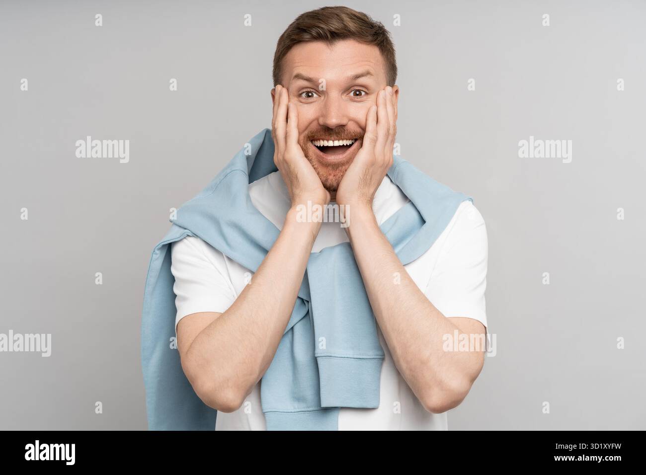Glücklicher Mann legt überraschend Hände auf die Wangen, fühlt aufrichtiges Glück Freude Freude vereinzelten Hintergrund Stockfoto