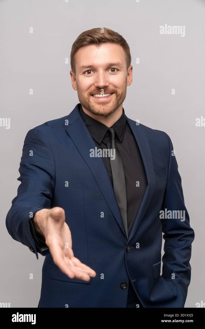 Ein lächelnder Geschäftsmann hält die Hand und bietet an, Geschäfte zu machen. Porträtmann, der die Handfläche zum Händewaschen auszieht Stockfoto