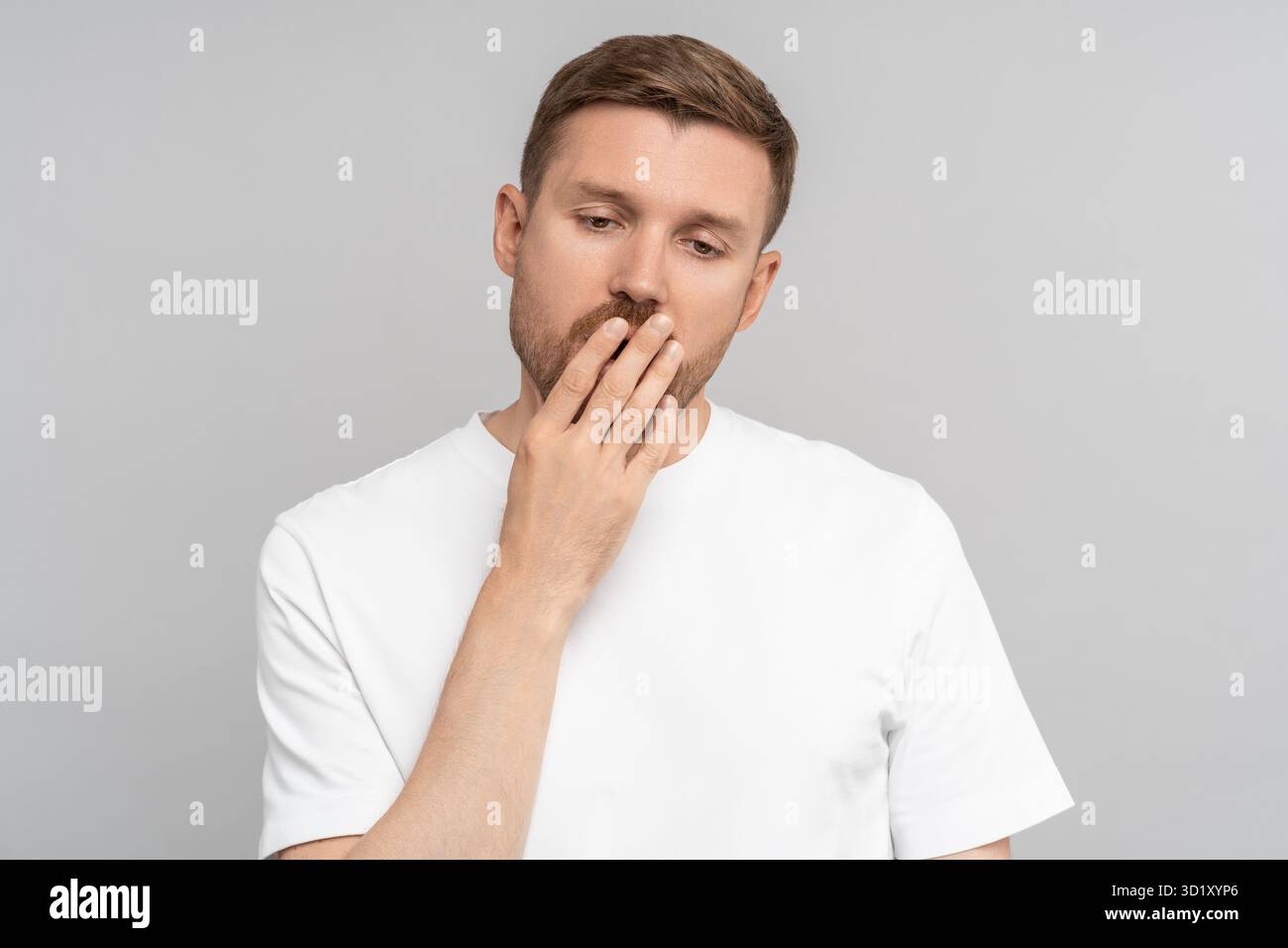 Verschlafener Gähner mit geschlossenen Augen geöffnetem Mund, der Hand auf grauem Hintergrund bedeckt. Stockfoto