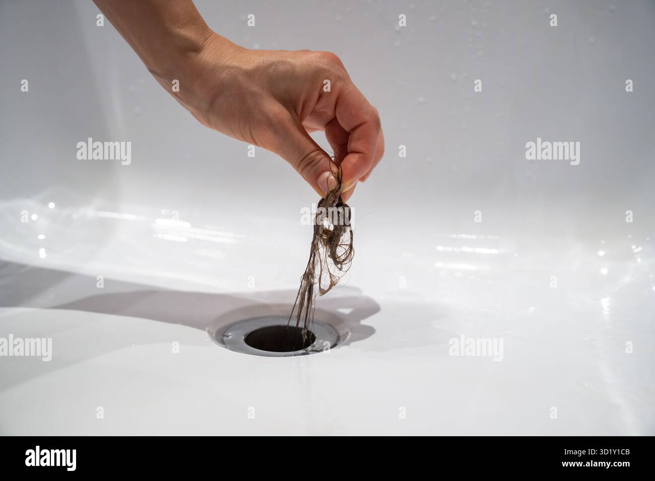 Die Wasserablauföffnung in der Badewanne ist zuhause mit Haarklumpen im Badezimmer verstopft. Stockfoto