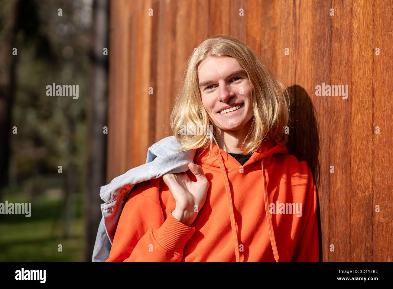 Porträt eines glücklichen europäischen Blonden lächelnd, schauen Sie in die Kamera, entspannen Sie sich im Freien Genießen Sie das sonnige Wetter. Stockfoto