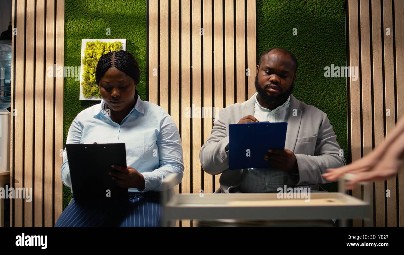 afroamerikanische Bewerber füllen Anmeldeformulare für Bewerbungsgespräche und offene Stellen aus, um eine erfolgreiche Rekrutierung und ein Treffen mit der Personalabteilung zu gewährleisten. Qualifikationen notieren. Kamera A.. Stockfoto