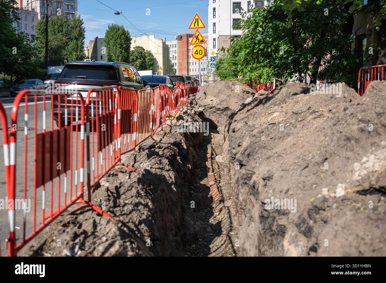Graben für die Verlegung von elektrischen Kabeln in Stadtstraßen, Versorgungsarbeiten für den Austausch von Rohrleitungen. Stockfoto