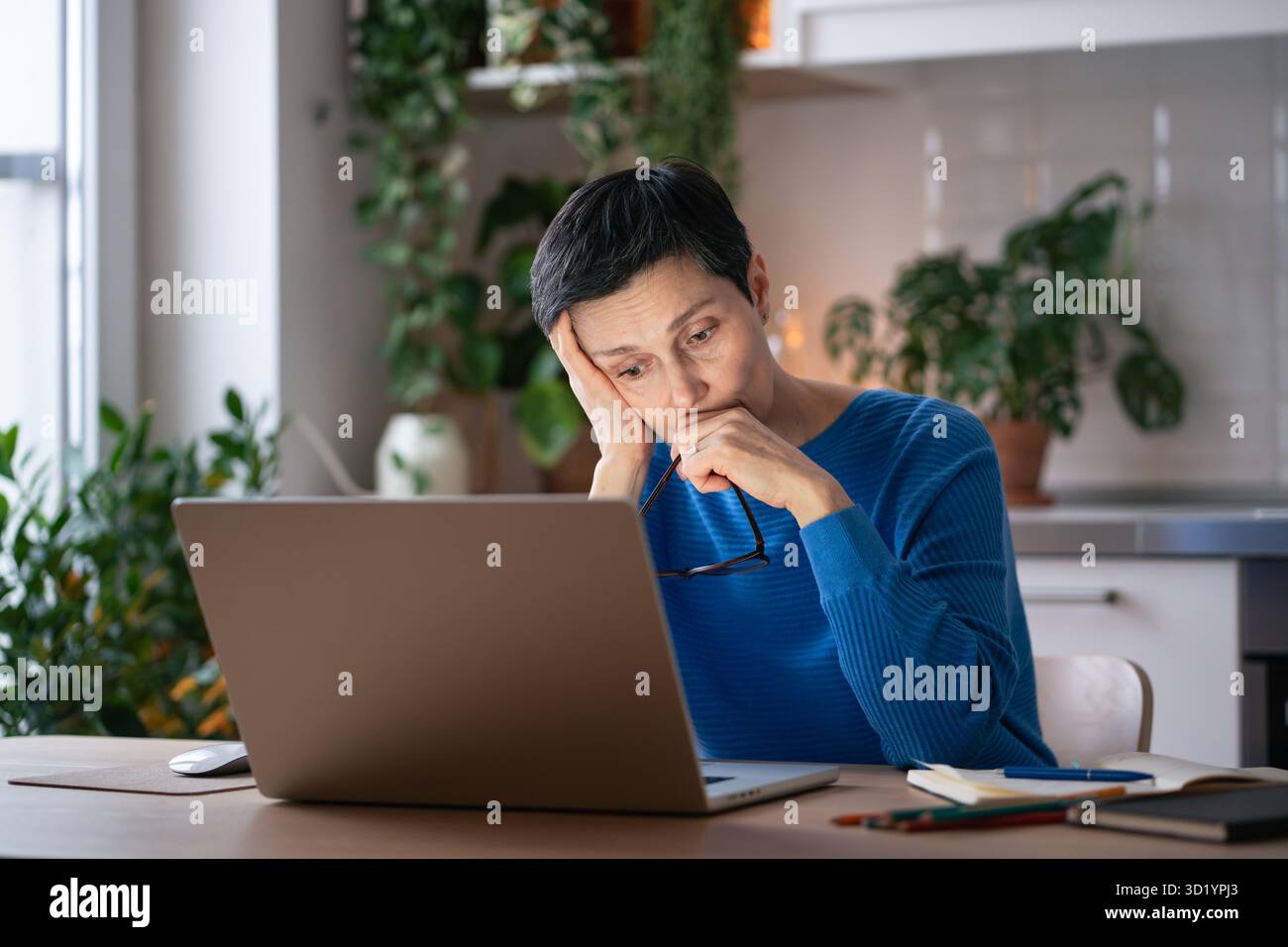Verbrannte traurige Frau zu Hause, leidet unter Kopfschmerzen durch übermäßige Bildschirmzeit und Arbeitsstress am Laptop Stockfoto