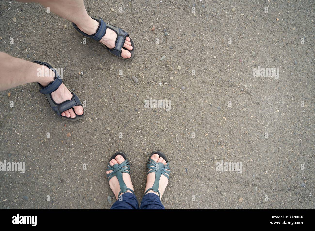 Sandelfüße auf Schotterpiste. Bequeme Sommerschuhe im Freien Stockfoto