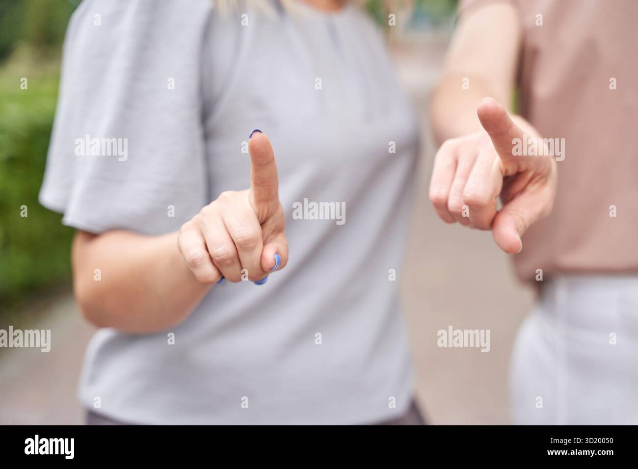 Zwei kaukasische Erwachsene, die mit Zeigefingern in lässiger Kleidung im Freien Gesten geben Stockfoto