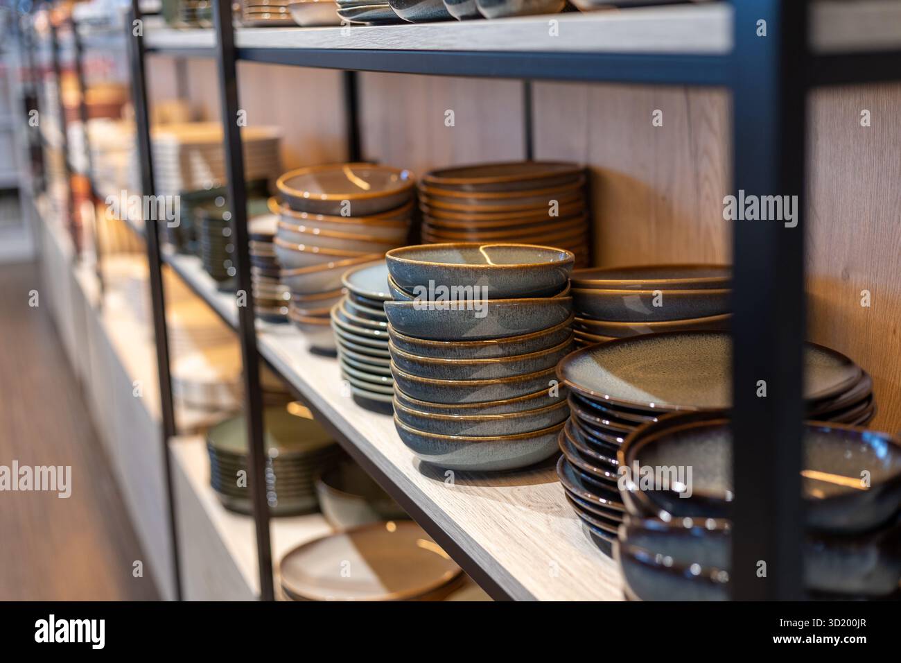 In den eleganten Regalen eines modernen Küchenartikelgeschäfts stehen Keramikplatten und -Schüsseln in verschiedenen Farben und Designs und sorgen so für ein stilvolles Shopping Stockfoto