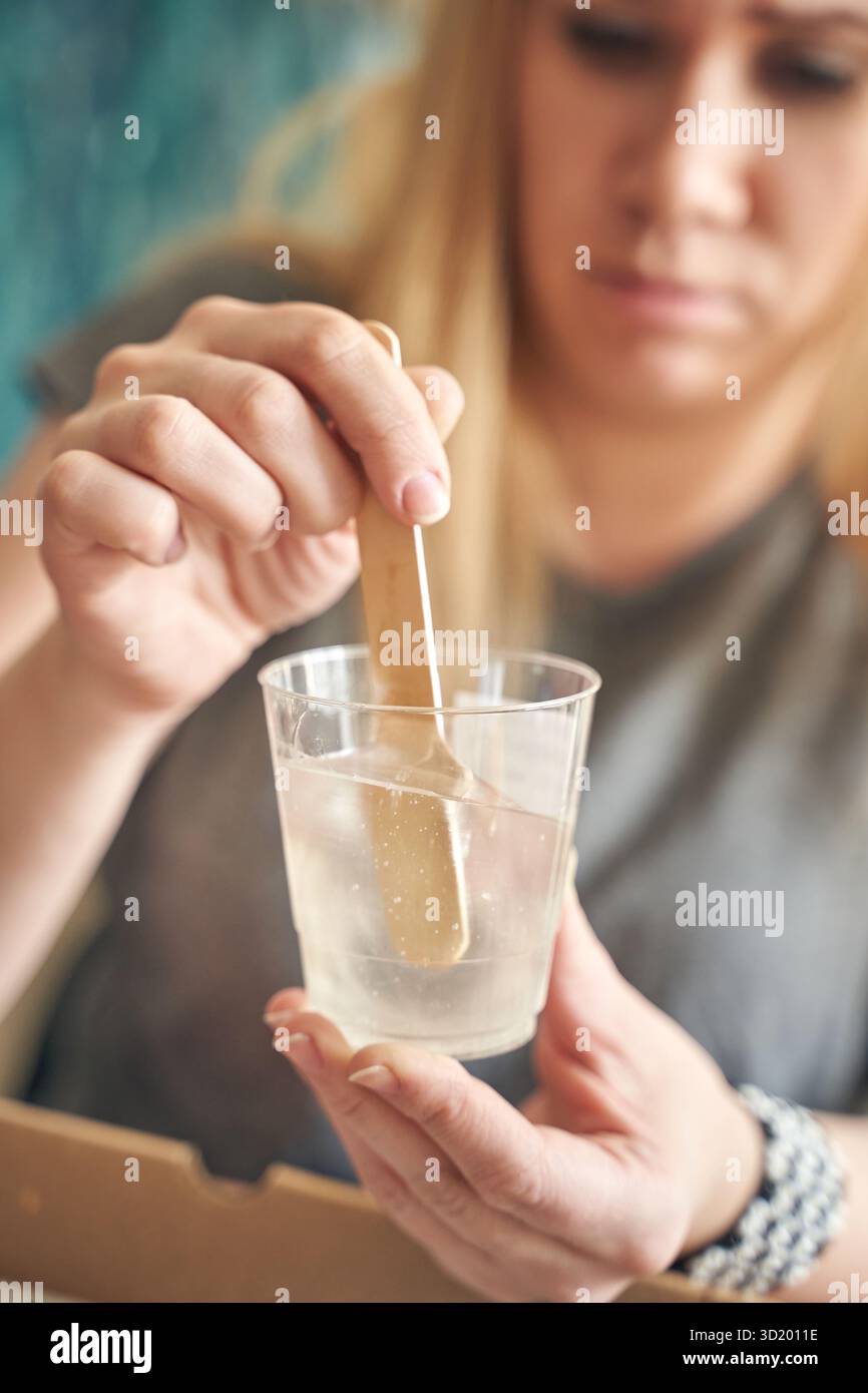 Kaukasische Erwachsene, die Kunstharz-Kunstharz-Kunsthandwerk in durchsichtigem Becher für heimwerker mischen Stockfoto
