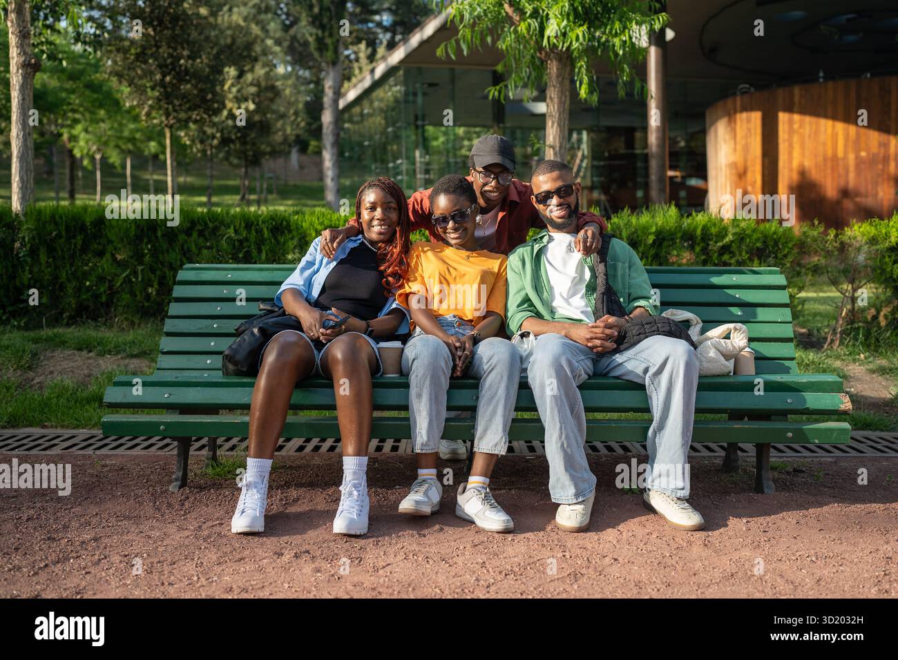 Glückliche junge Paare, schwarze Männer und Frauen, sitzen während des Doppeldatens auf der Parkbank und schauen in die Kamera Stockfoto