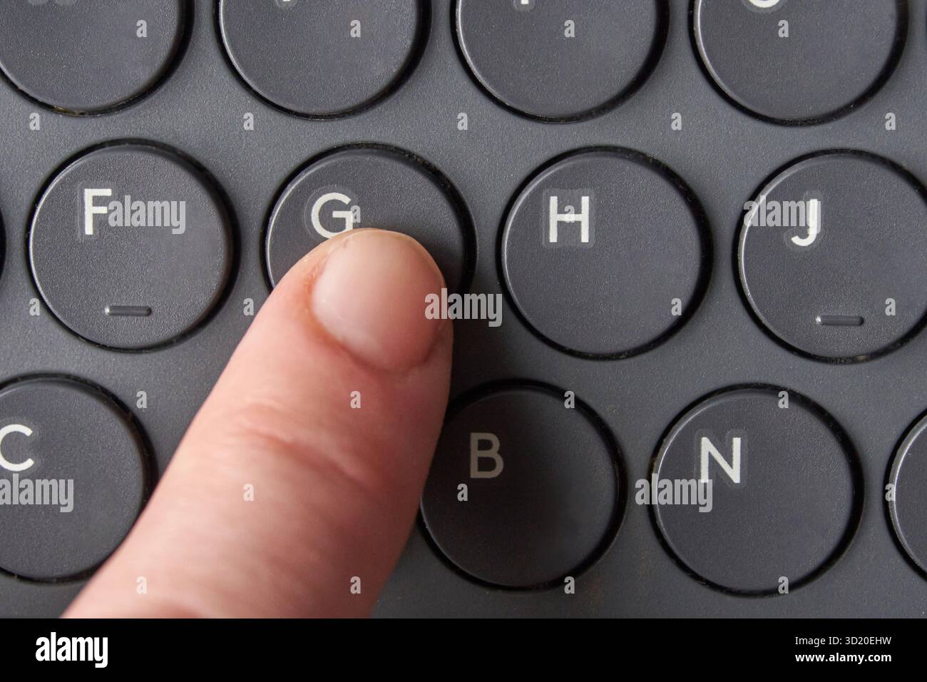 Nahaufnahme des Fingerdrucks der Taste g auf der runden schwarzen Tastatur Stockfoto