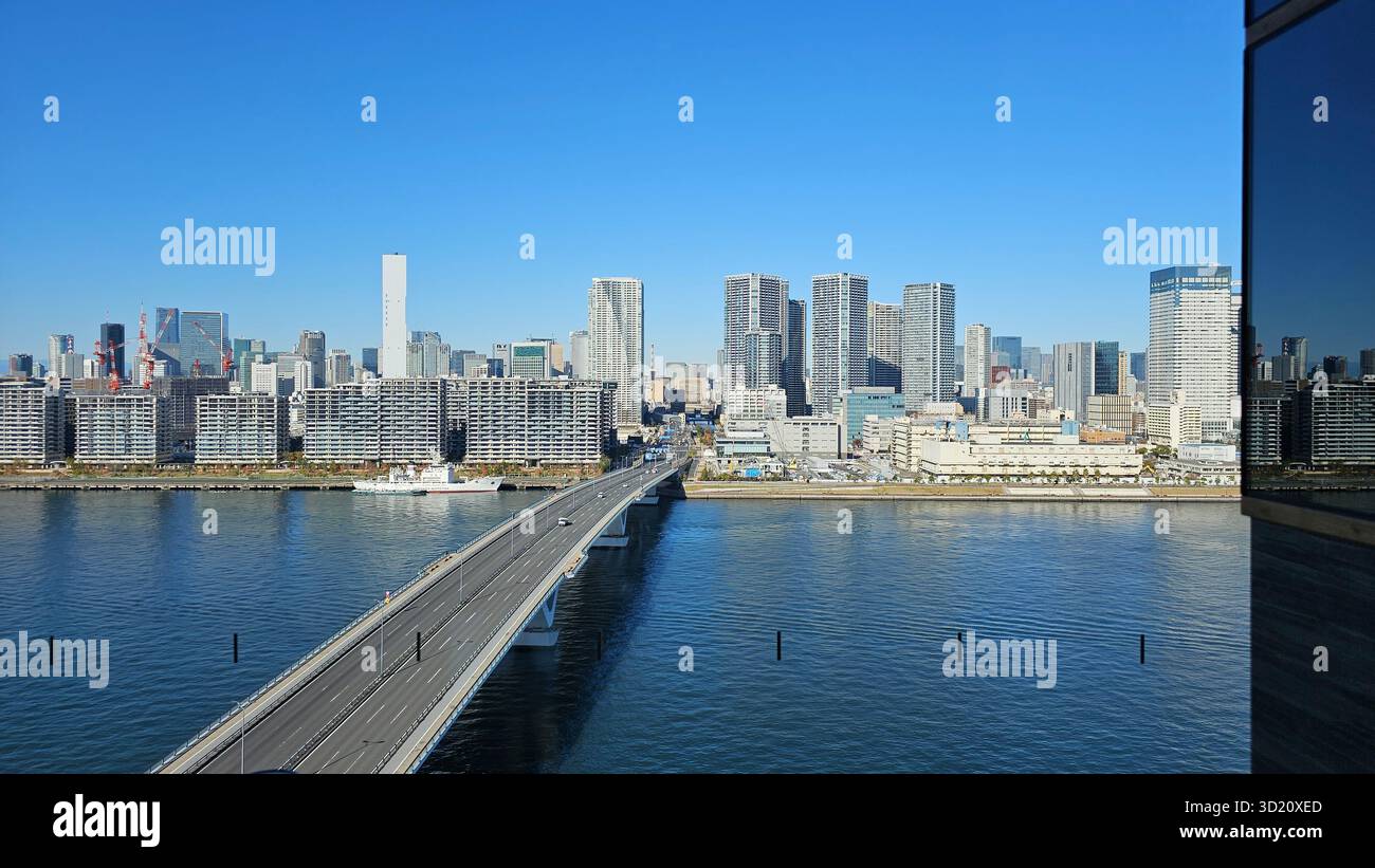 Morgensonnenlicht mit Blick auf den Sumida Fluss und die Harumi-Brücke der Bucht von Tokio Japan, eine Stadtlandschaft mit Wolkenkratzern und Verkehrsmitteln - Smartphone-aufgenommenes Stockfoto