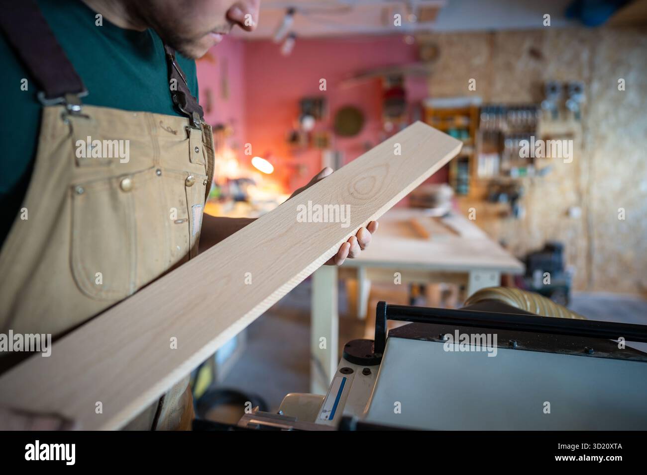 Konzentrierter, aufmerksamer Handwerker, der die Holzplanke sorgfältig überprüft, bevor er in der Tischlerei bastelt Stockfoto