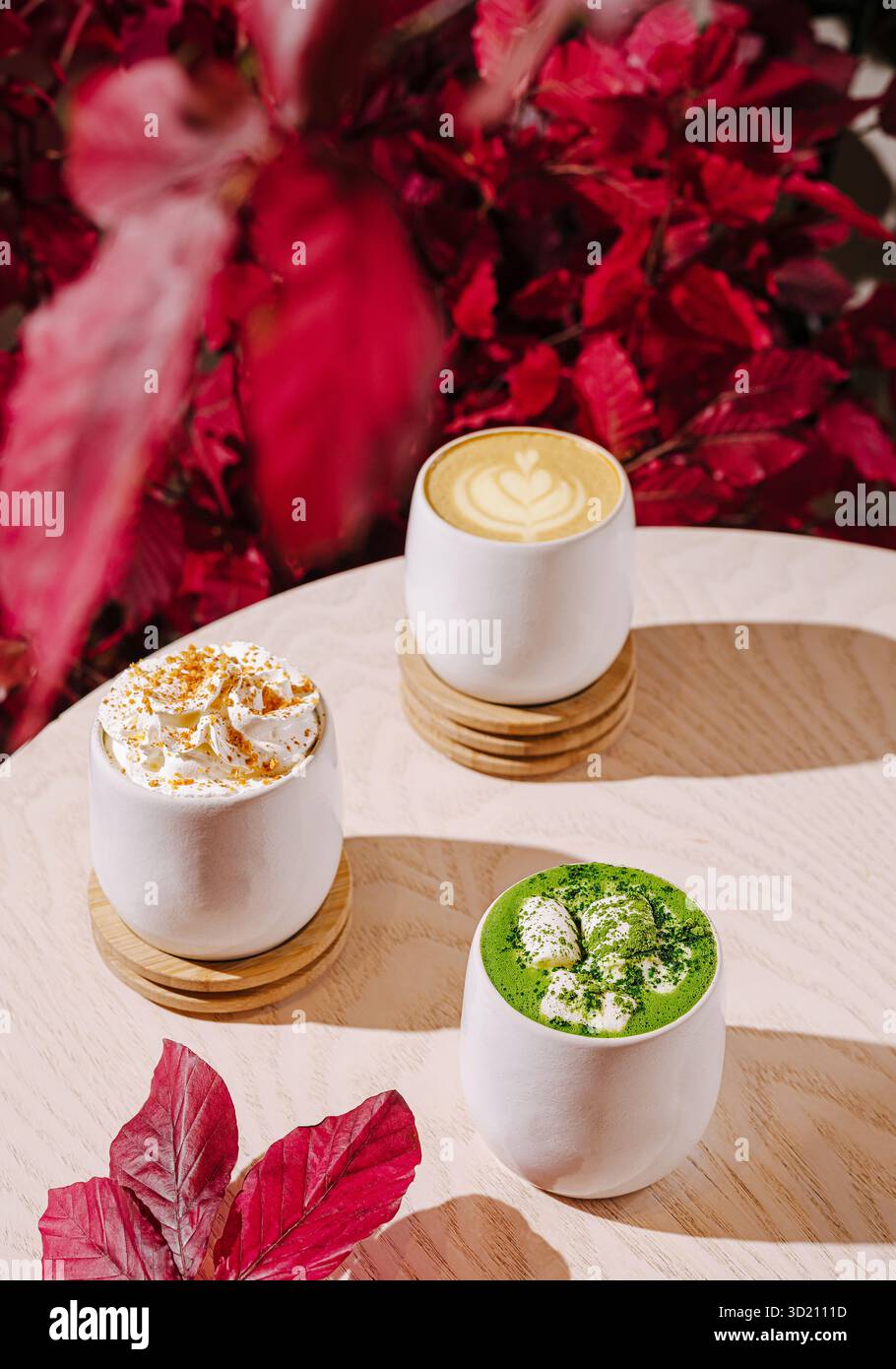 Warme Getränke werden in stilvollen Tassen mit Herbstlaub-Akzenten in einem gemütlichen Café serviert Stockfoto