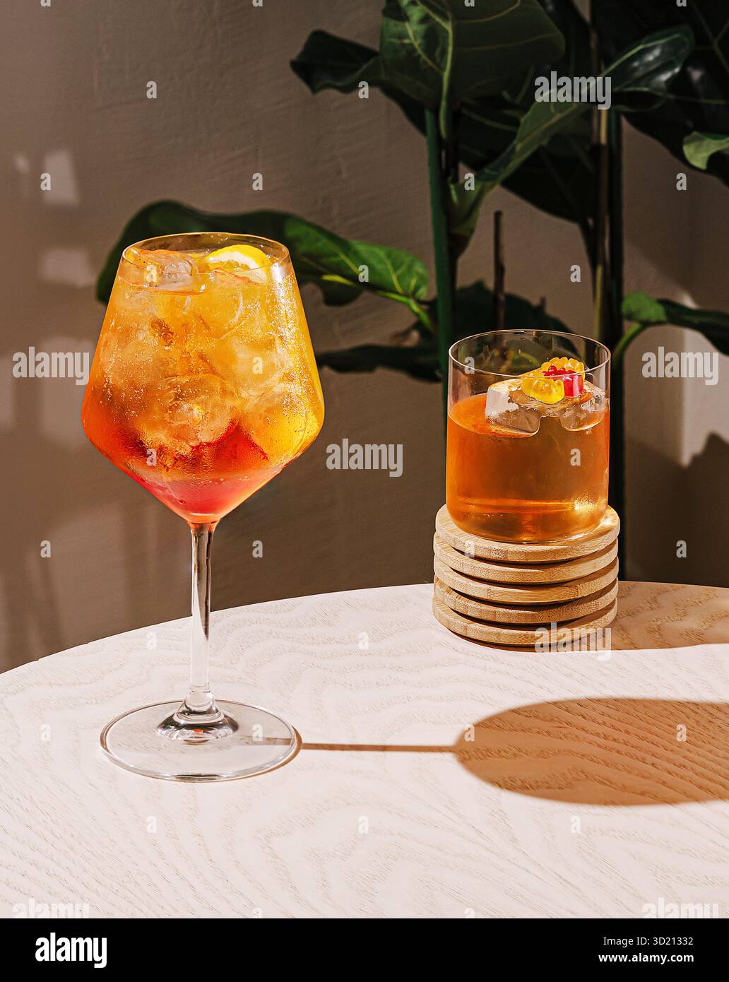 Farbenfrohe Cocktails werden auf einem Tisch mit einer üppigen grünen Pflanze in einem modernen Ambiente serviert Stockfoto