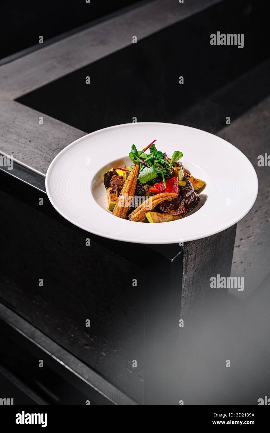 Gourmet-Gericht mit gegrilltem Gemüse und herzhafter Fleischzubereitung in einem modernen Ambiente Stockfoto