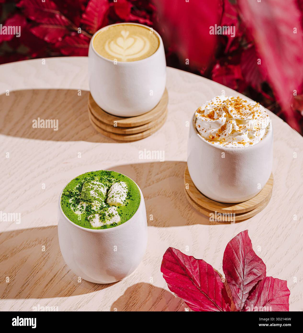 Warme Getränke werden in stilvollen Tassen mit Herbstlaub-Akzenten in einem gemütlichen Café serviert Stockfoto