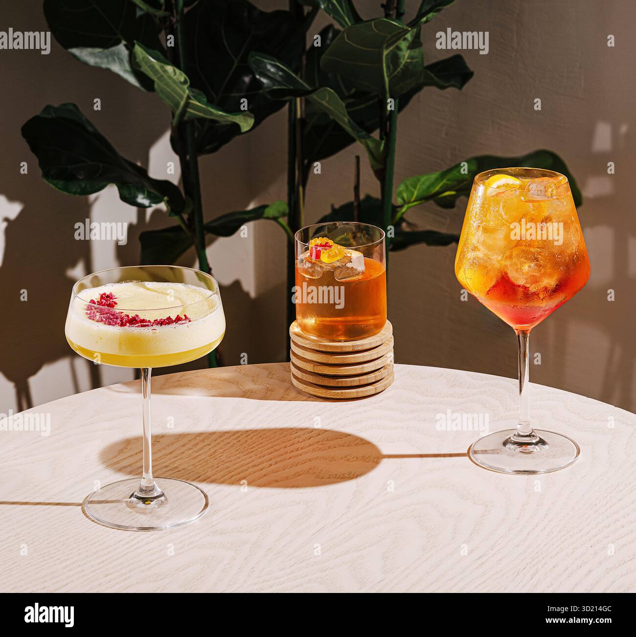 Farbenfrohe Cocktails werden auf einem Tisch mit einer üppigen grünen Pflanze in einem modernen Ambiente serviert Stockfoto