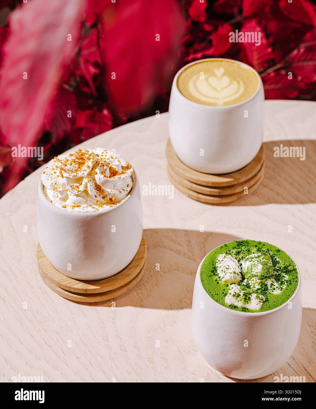 Warme Getränke werden in stilvollen Tassen mit Herbstlaub-Akzenten in einem gemütlichen Café serviert Stockfoto