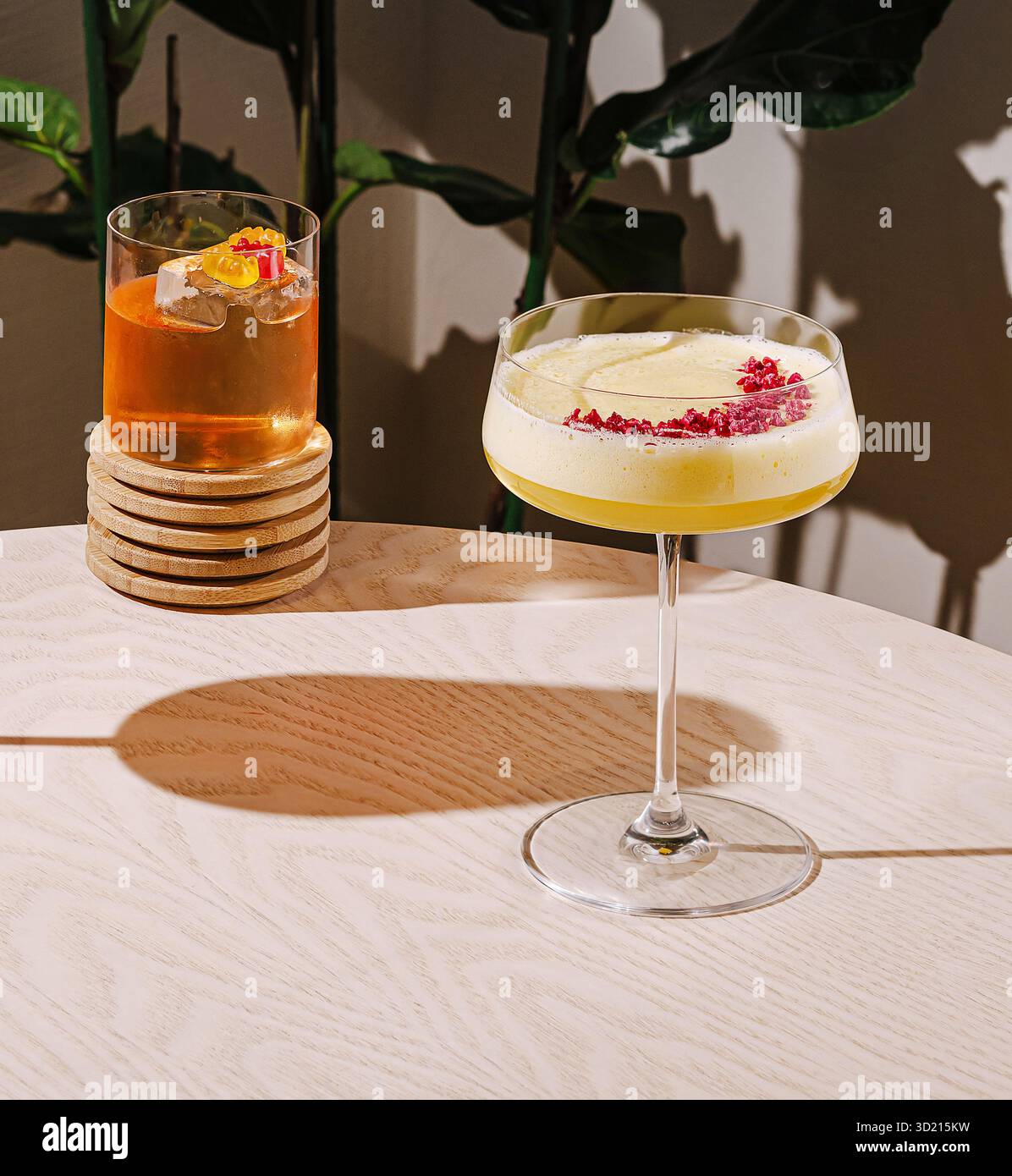 Farbenfrohe Cocktails werden auf einem Tisch mit einer üppigen grünen Pflanze in einem modernen Ambiente serviert Stockfoto