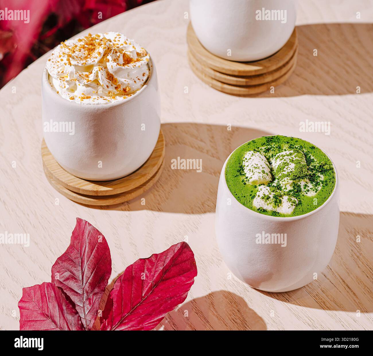 Warme Getränke werden in stilvollen Tassen mit Herbstlaub-Akzenten in einem gemütlichen Café serviert Stockfoto