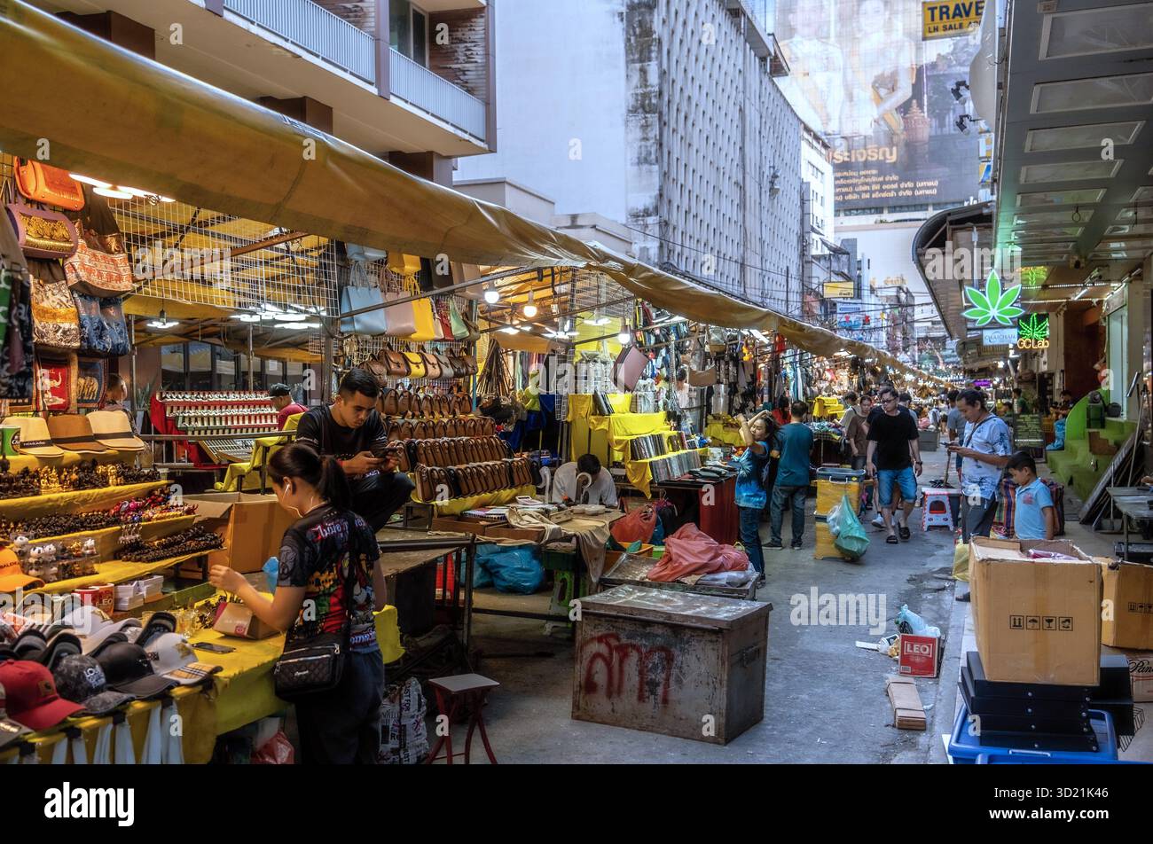 Händler, die Souvenirs und Kleidung auf einem typischen thailändischen Straßenmarkt verkaufen Stockfoto