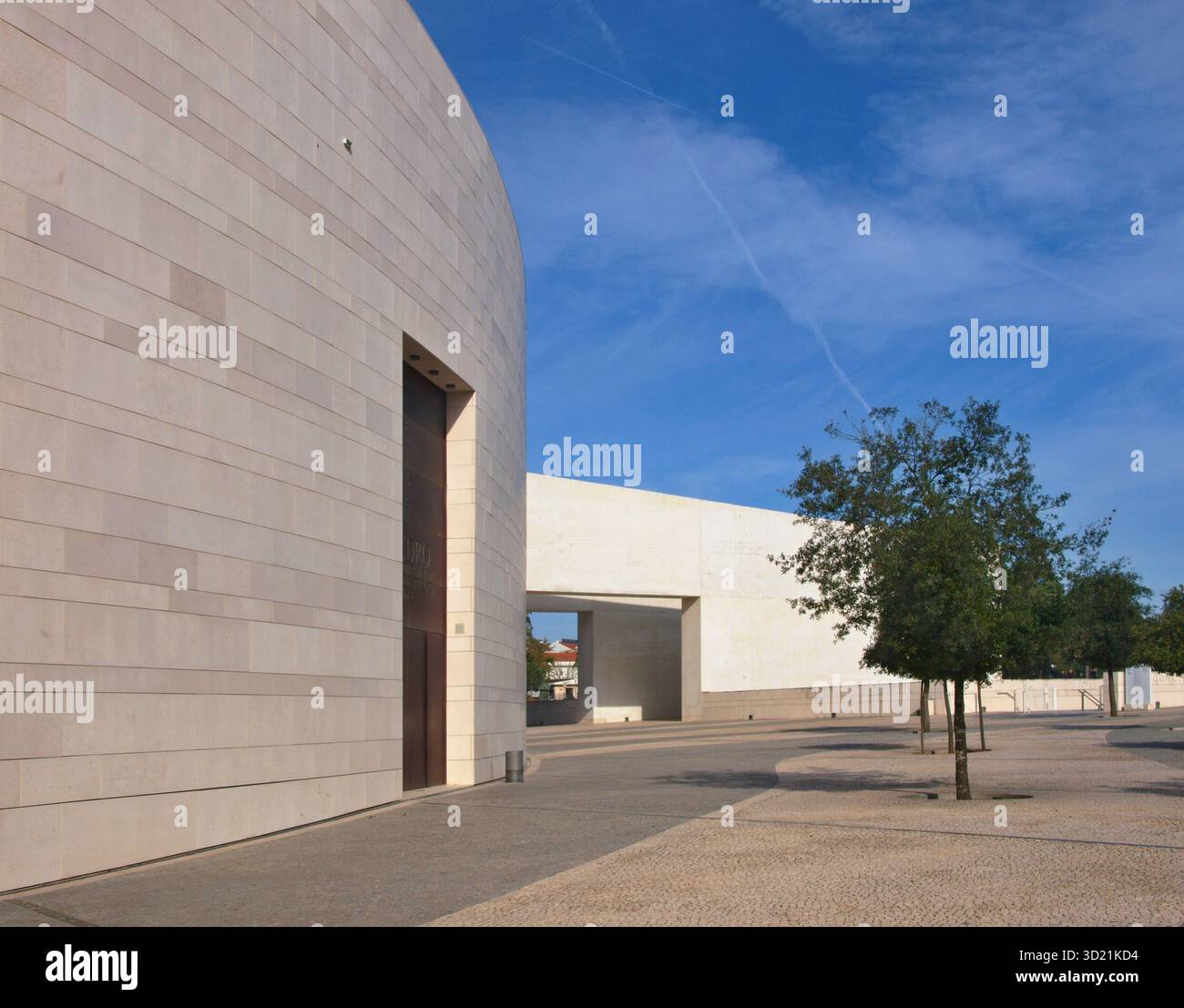 Große, geschwungene Wand des modernen Centro Cultural de Belém mit Bäumen unter blauem Himmel Stockfoto