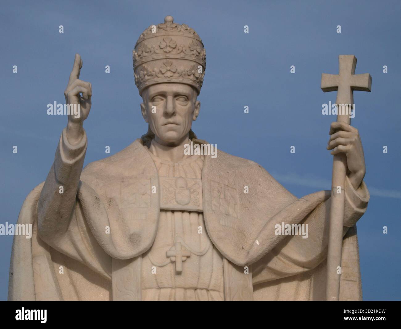 Imposante Marmorstatue von Papst Johannes Paul II., der seinen rechten Zeigefinger hebt und ein Kreuz hält Stockfoto