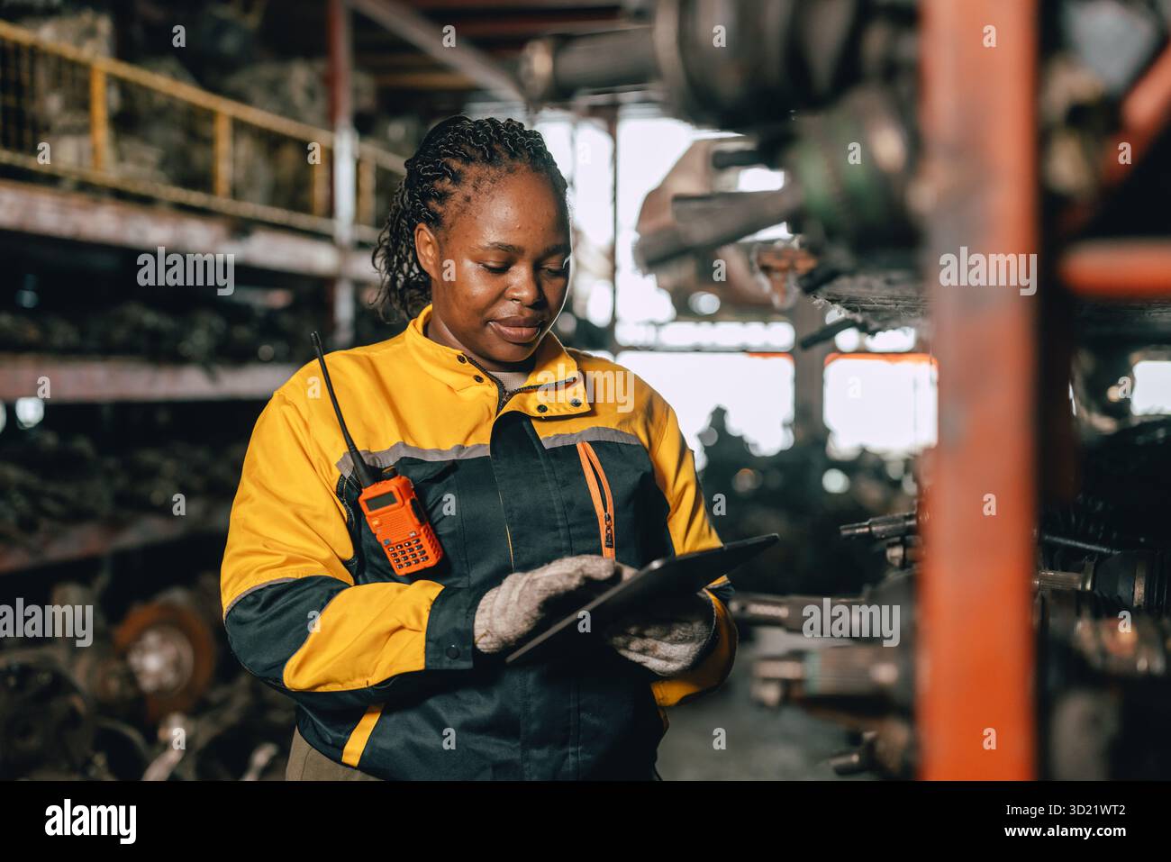Glückliche schwarze afrikanische Ingenieurinnen arbeiten gerne in alten Lagerlagern für gebrauchte Metallmaschinenteile. Stockfoto